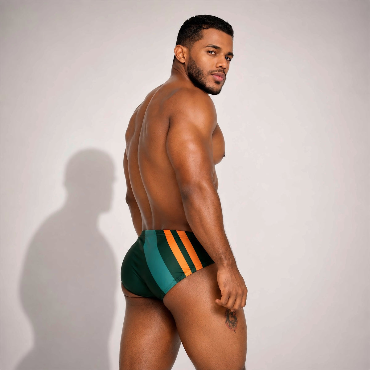Bañador deportivo para hombre verde con franjas naranjas, vista trasera – Brief Sport de EQUAL Swimwear