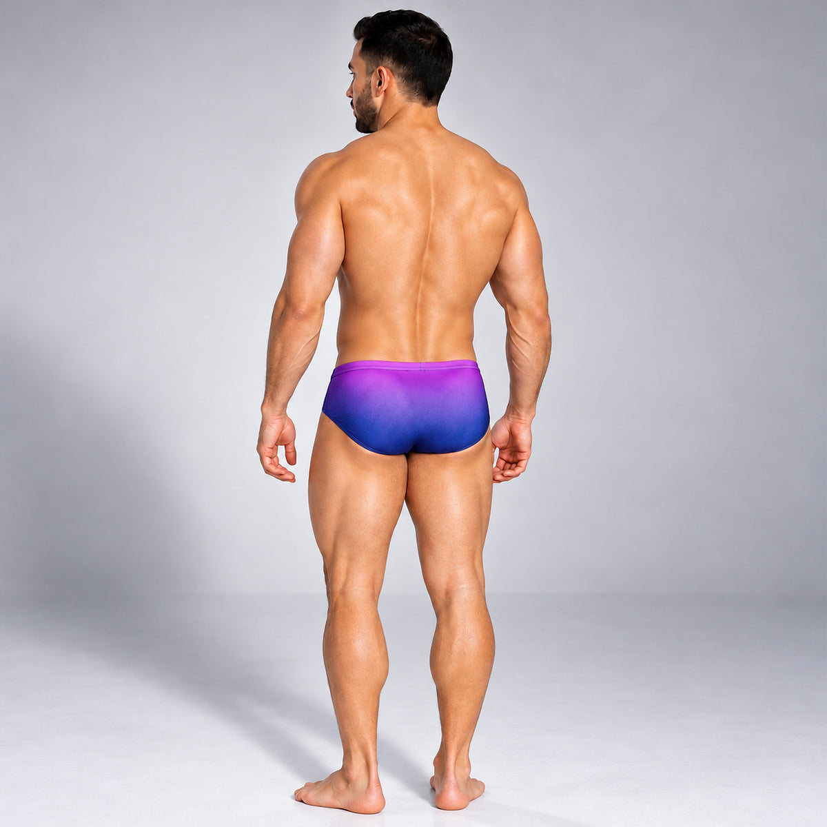 Traje de baño para hombre púrpura con degradado azul, vista trasera en modelo.
