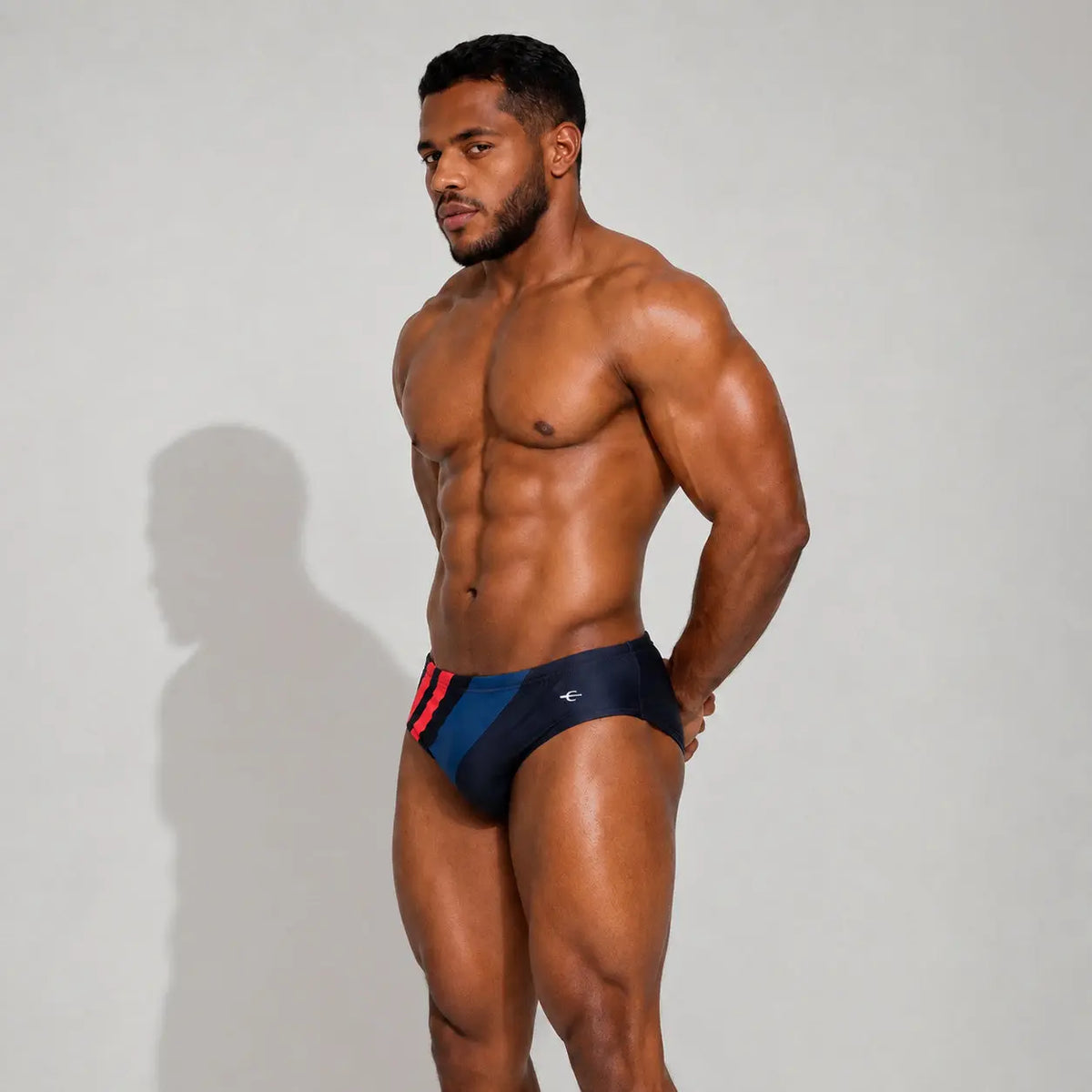 Brief de baño deportivo para hombre azul con franjas rojas, vista de perfil – Brief Sport de EQUAL Swimwear